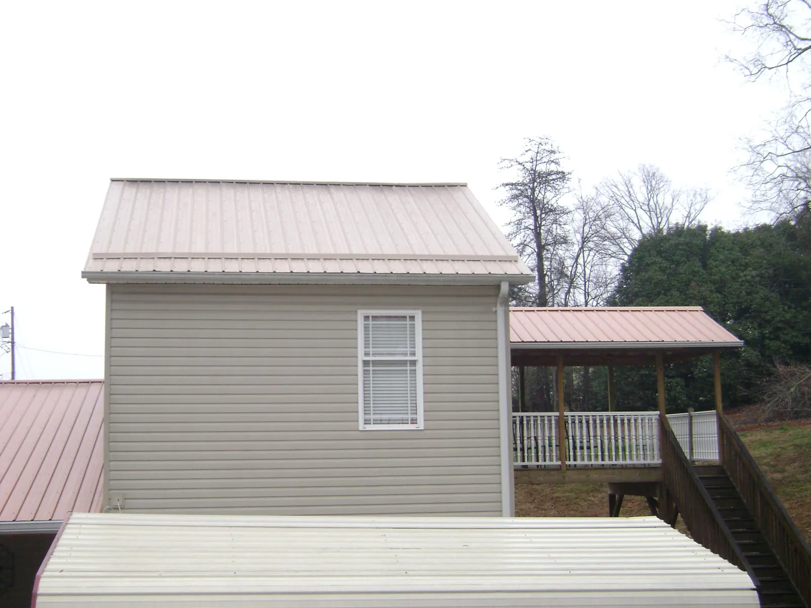 Tan metal roofs on a two story addition and attached porch, from a Roof Replacement job in Riceville